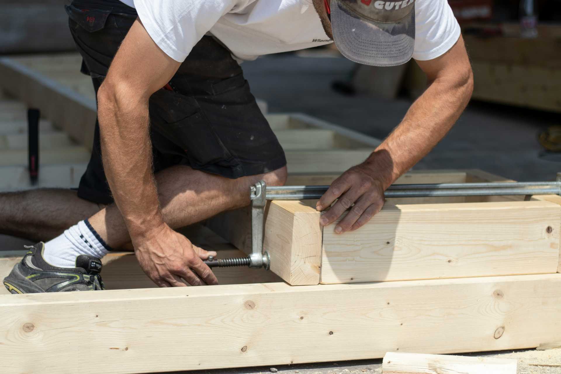 Technician assembling a wooden structure on site.
